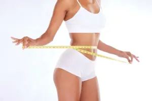 Weight loss concept with a woman measuring her waist after body transformation